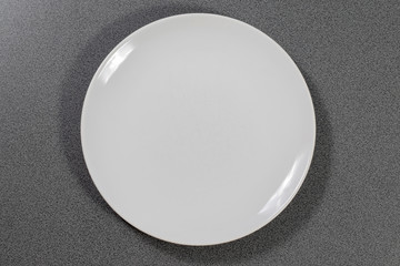 Weißer Teller aus Porzellan auf einem grauen Tisch in der Küche 