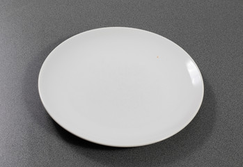 Weißer Teller aus Porzellan auf einem grauen Tisch in der Küche 