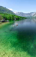 Concept picture of summer time at lake bohinj in Slovenia with red canoe in emerald color lake.