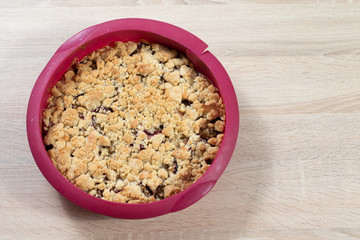 Frischer Pflaumenkuchen in Backform auf Holztisch