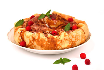 Round pancakes are placed in a heap. It is decorated in the form of a cake. The dish is decorated with whipped cream, fresh raspberries and a sprig of mint. Pancakes are the main dish of Maslenitsa.