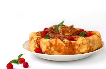 Round pancakes are placed in a heap. It is decorated in the form of a cake. The dish is decorated with whipped cream, fresh raspberries and a sprig of mint. Pancakes are the main dish of Maslenitsa.