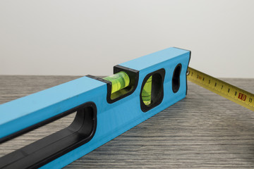 Tools, blue bubble level and measuring tape on a decorated wood table