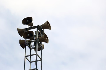 Loudspeaker tower for public relations on metal pole isolated in the bright sky.