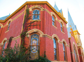 Beautiful church building in Greenville, TX, USA. Bright red brick wall of house with stained-glass...