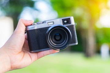 Soft focus photo of retro-style rangefinder camera. Black-and-gray camera on hand.
