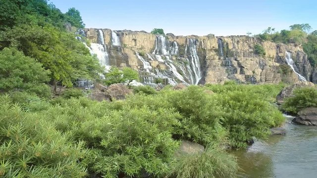 camera shows brushwoods and rocks on foreground by Pongour waterfall