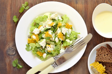Salad with corn, greens, feta with mayonnaise sauce, top view