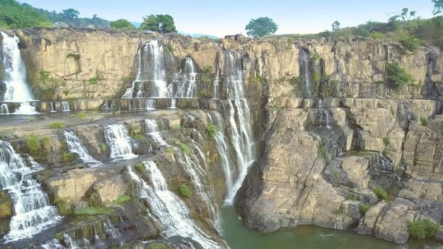 distant tourists climb rocks to watch waterfall
