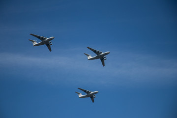 Military airplanes lined up in a row during the Russian military parade on bright blue sky with clouds in spring