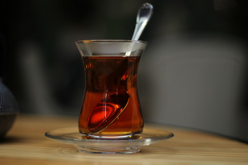 Glass cup of black tea, teaspoon on wooden table