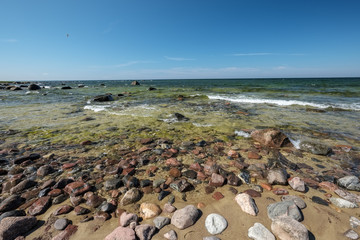 Fototapeta na wymiar rocky sea beach with waves and sunny day