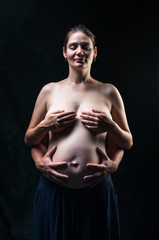 Obraz na płótnie Canvas Pregnant girl on black background with big belly