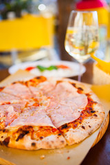 Italian food dinner. Pizza with tomato prosciutto mozzarella glass white wine summer outdoor restaurant