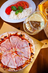 Italian food dinner. Pizza with tomato prosciutto mozzarella glass white wine summer outdoor restaurant