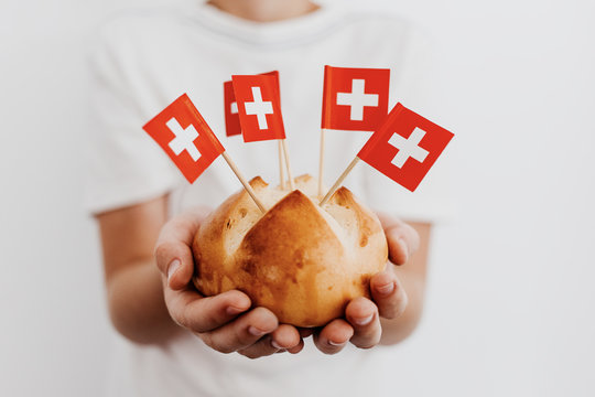 Traditional swiss bread buns called in German 1.Augustweggen baked in Switzerland to celebrate Swiss National Day on August 1st. Body parts, children hands holding bread. 