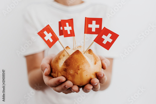 Traditional swiss bread buns called in German 1.Augustweggen baked in Switzerland to celebrate Swiss National Day on August 1st. Body parts, children hands holding bread.