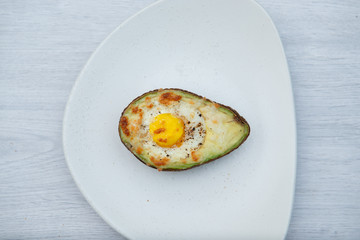 One egg baked in avocado on wooden table
