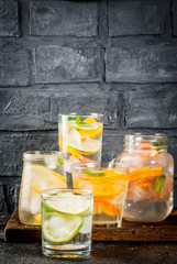 Summer healthy cocktails, set of various citrus infused waters, lemonades or mojitos, with lime lemon orange grapefruit, diet detox beverages, in different glasses dark background copy space