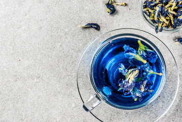 Healthy drinks, organic blue butterfly pea flower tea with limes and lemons, grey concrete...