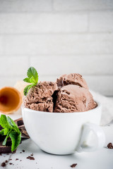Homemade chocolate ice cream served with fresh mint, dark chocolate and waffle ice cream cones, white marble background copy space