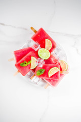 Sweet summer watermelon and lime popsicles with sliced watermelon and mint, on white marble background copy space