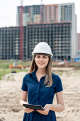 Female construction engineer. Architect with a tablet computer at a construction site. Young Woman look in camera, building site place on background. Construction concept