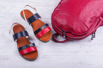 Fashionable women's sandals and backpack on white wooden background.