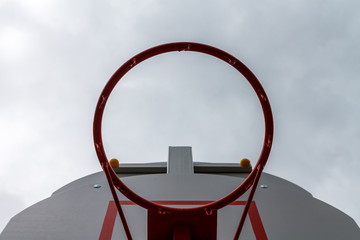 Red basketball ring on a background of a gray sky.