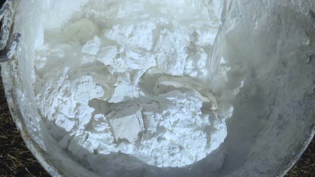 Chemical reaction. Lime slaking in a stainless steel bucket. It is used for whitewashing trees.