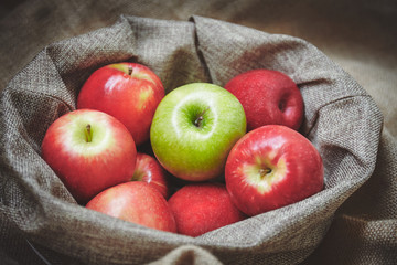 Red apple and green apple in basket with sackcloth background texture, Organic fresh apples side view