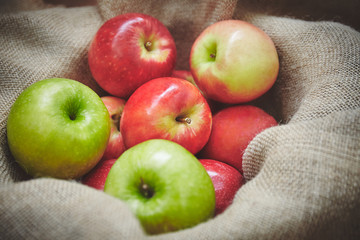 Harvest time, organics apples from nature in basket on sackcloth background texture