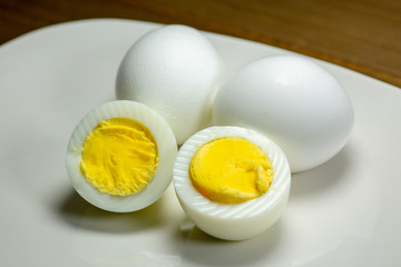 Hardboiled eggs with one cut in half on a plate at the kitchen table