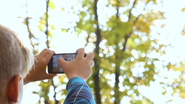 Little cute child taking pictures of beautiful nature landscape using digital camera of his mobile phone. Real time full hd video footage.