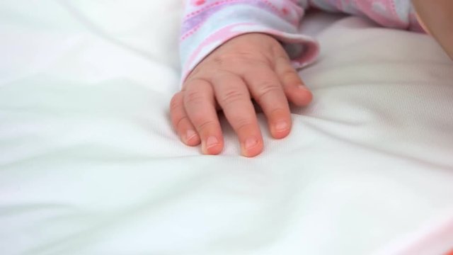 Small delicate hand of newborn. Infant baby hand on white blanket.