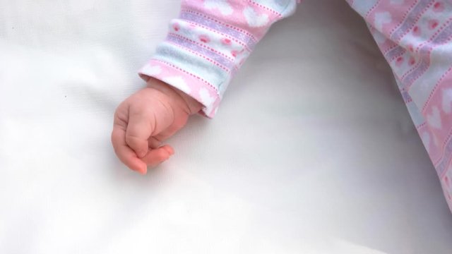 Hand of newborn girl on white carpet. Sweet infant child lying on white blanket. Little arm of newborn.