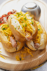 Snack, fast food, hot dogs with Bavarian sausages and grated cheddar on the wooden tray. Travel food concept.