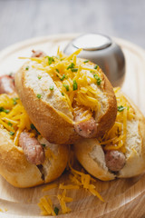 Snack, fast food, hot dogs with Bavarian sausages and grated cheddar on the wooden tray. Travel food concept.