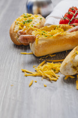 Snack, fast food, hot dogs with Bavarian sausages and grated cheddar on the wooden tray. Travel food concept.