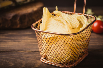 Fototapeta premium Crispy potato chips in copper basket on old wooden background served with club sandwich. Healthy fast food concept. Retro style toned.