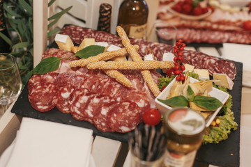 delicious meat plate on wedding reception. table with salami, bacon, prosciutto and smoked meat,basil and bread in restaurant. luxury catering. italian cuisine