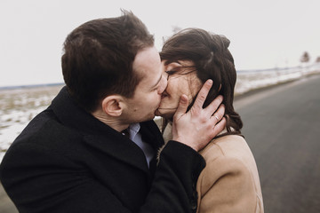 sensual bride with windy hair and groom embracing on road. happy couple hugging  and kissing in...