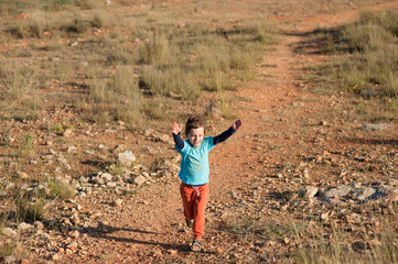 one happy running little boy refugee among desert near border in hot summer day