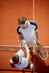 Tennis instructor congratulate to young player  .