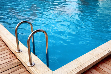 Modern swimming pool with step ladder at resort