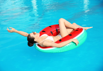 Beautiful young woman wearing bikini on inflatable ring in swimming pool
