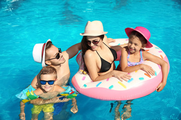 Young family with little children in swimming pool on sunny day
