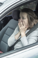 A frightened, shocked woman driving a car.