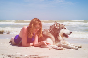 Happy woman and husky lay at beach