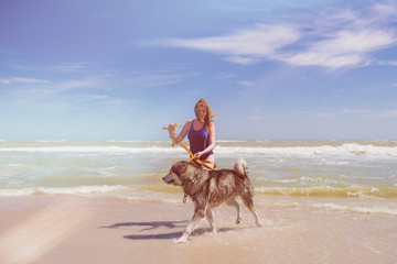 Woman smile during walk with husky at beach